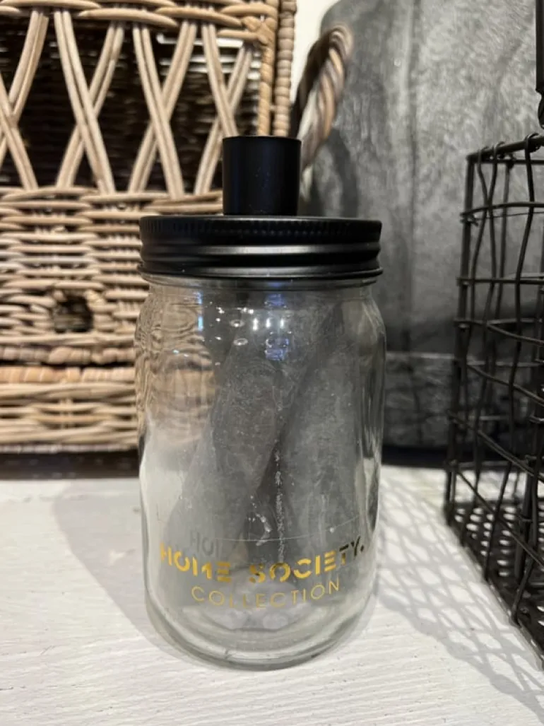 Glazen pot met drie grijze kaarsen